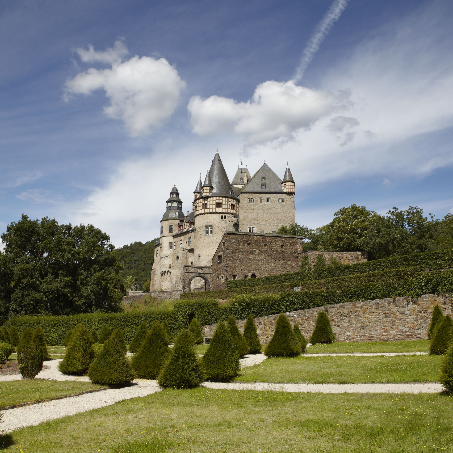 Garten mit getrimmten Büschen vor Bäumen und Schloss Bürresheim