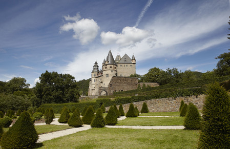 Garten mit getrimmten Büschen vor Bäumen und Schloss Bürresheim